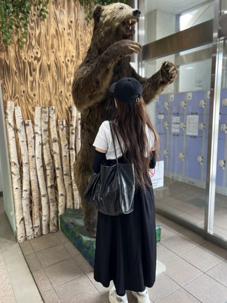 身長168cmの女性がヒグマの前に立つ画像